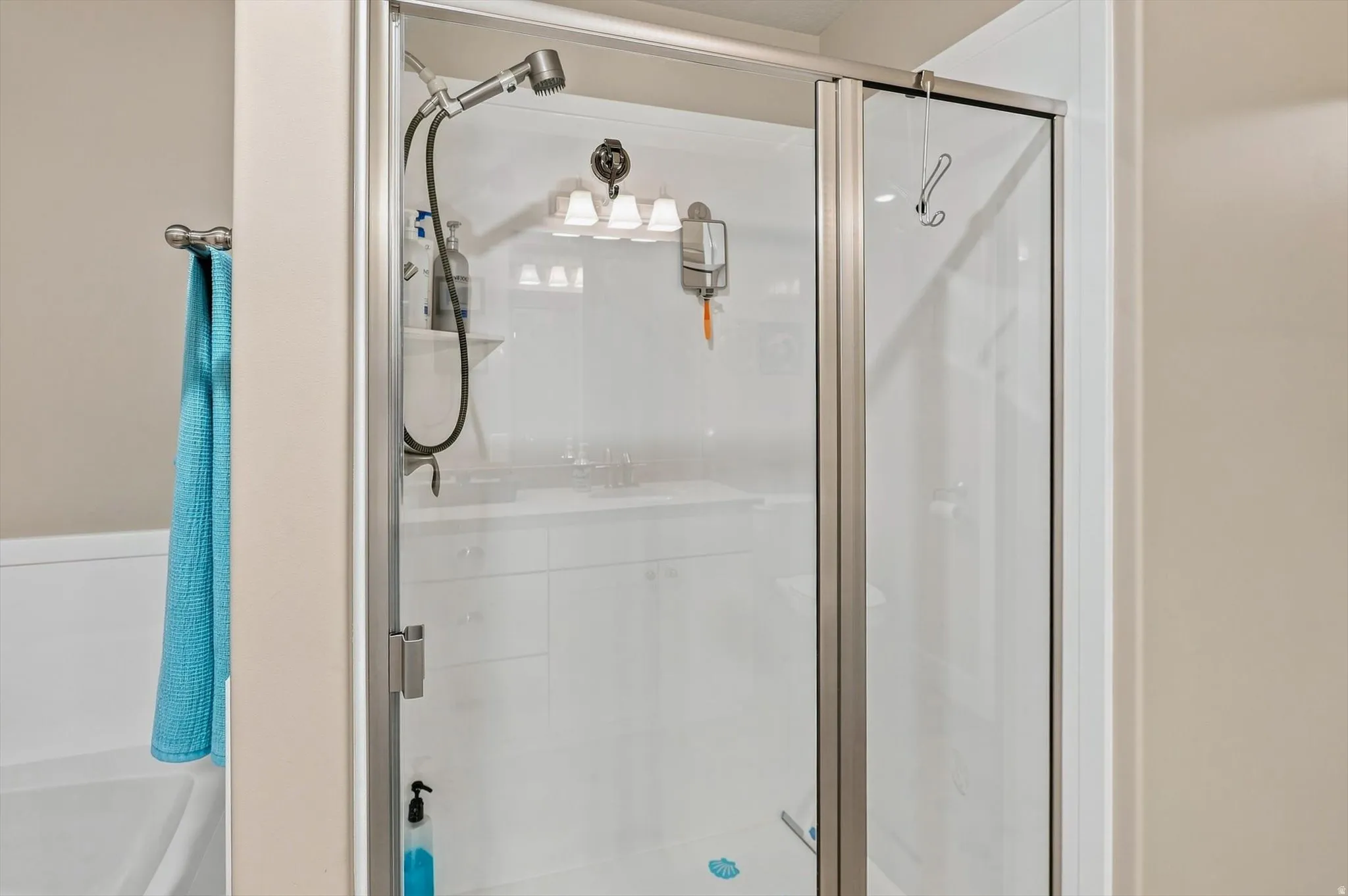 Walk-in shower featuring a clear glass enclosure with brushed nickel framing, a built-in shelf, and a handheld showerhead