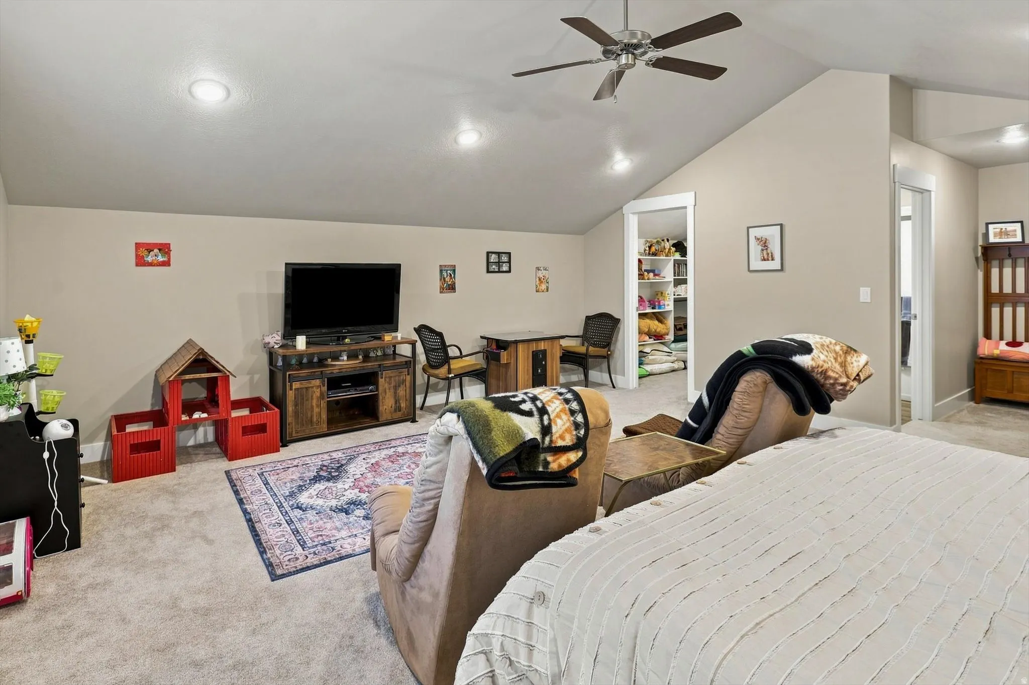 Spacious carpeted room featuring a ceiling fan, recessed lighting, and an angled ceiling