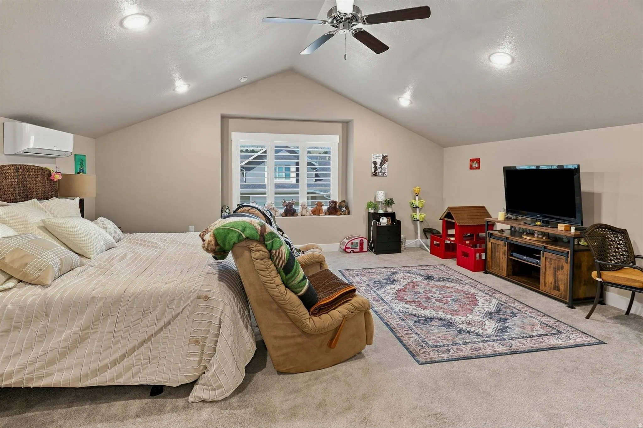 Spacious carpeted room featuring a vaulted ceiling with recessed lighting, a ceiling fan, and a window with plantation shutters
