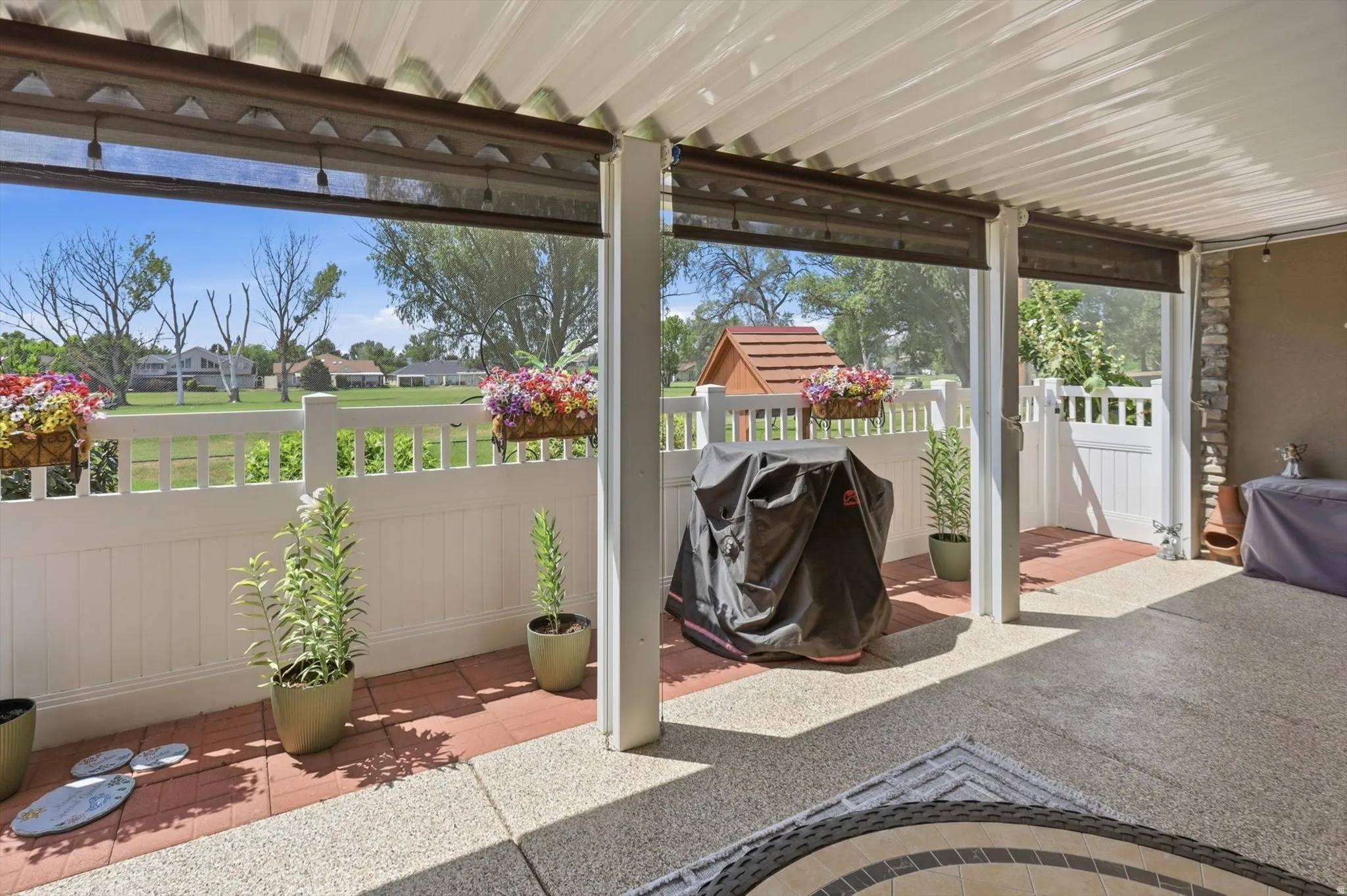 Covered patio featuring a textured concrete floor and a white vinyl fence