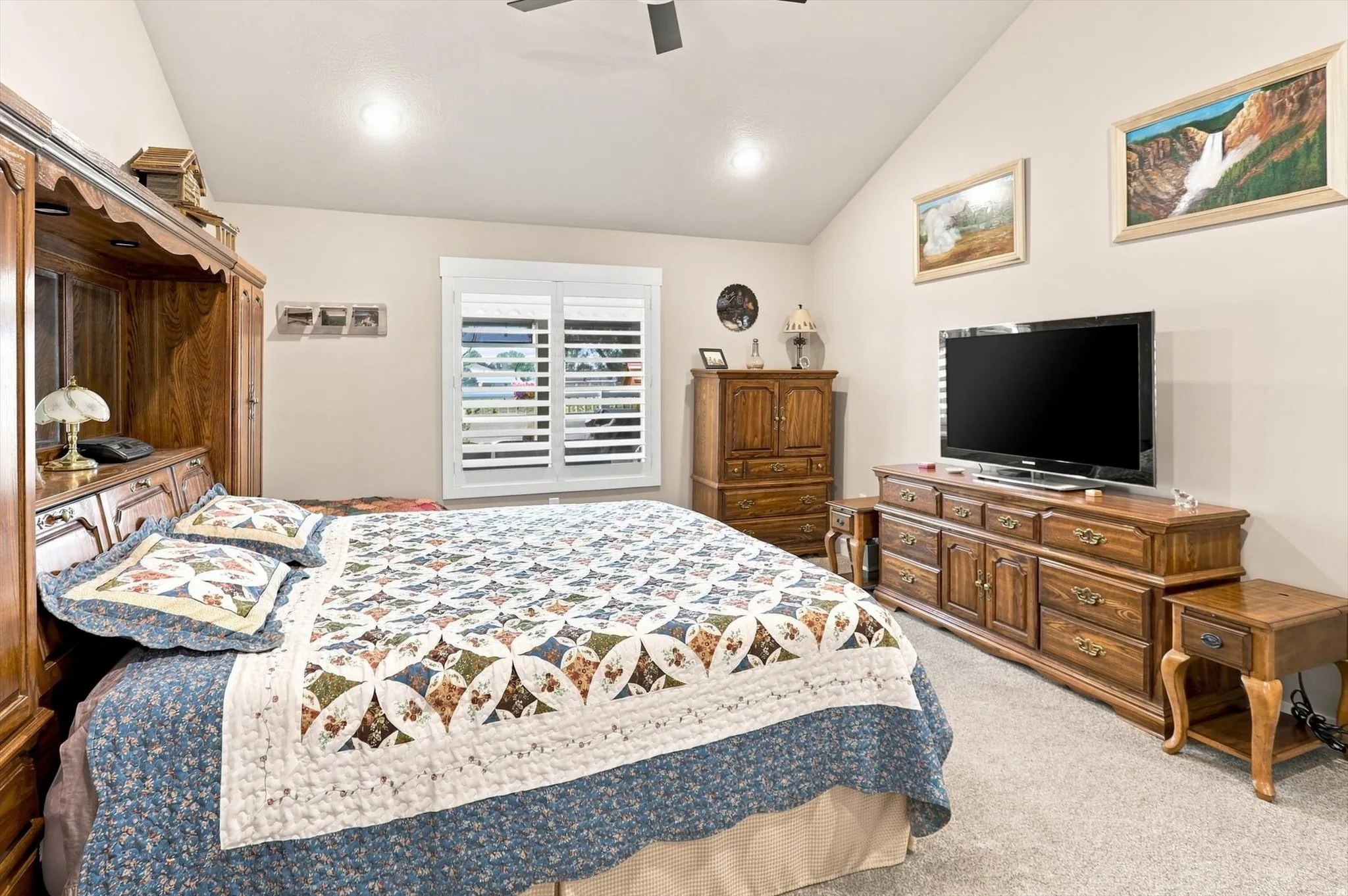 Spacious interior room featuring a vaulted ceiling, neutral wall paint, and plush carpeting