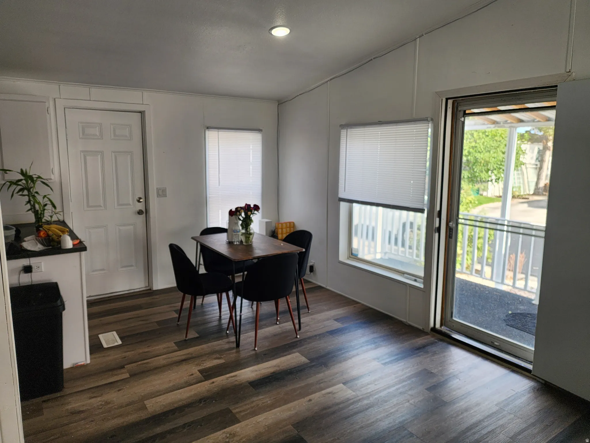 Open-concept living space featuring wood-finish flooring, white walls, and a sliding glass door