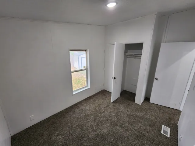 Carpeted room with a single window, recessed ceiling light, and closet with bi-fold doors