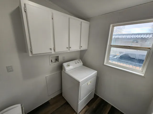 Dedicated laundry area featuring dark wood-finish flooring, white panel walls, and upper cabinetry