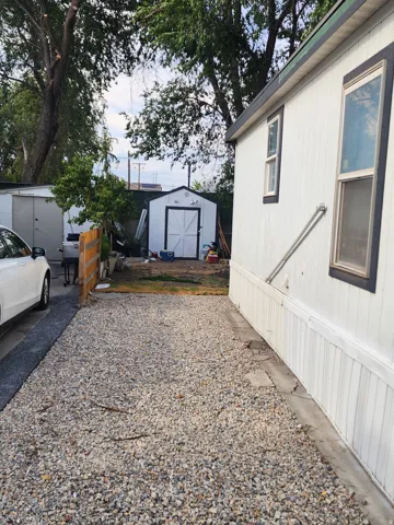 Gravel parking area leading to a white storage shed with double doors