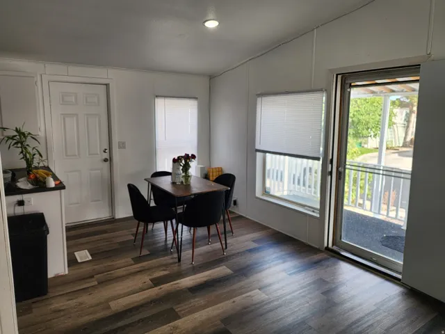 Open-concept living space featuring wood-finish flooring, white walls, and a sliding glass door
