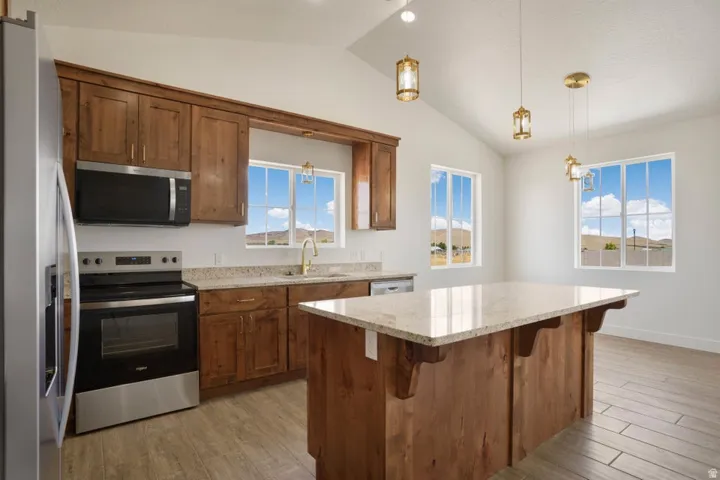 Kitchen featuring a central island with a light-toned countertop, wood-finish cabinetry, and stainless steel appliances