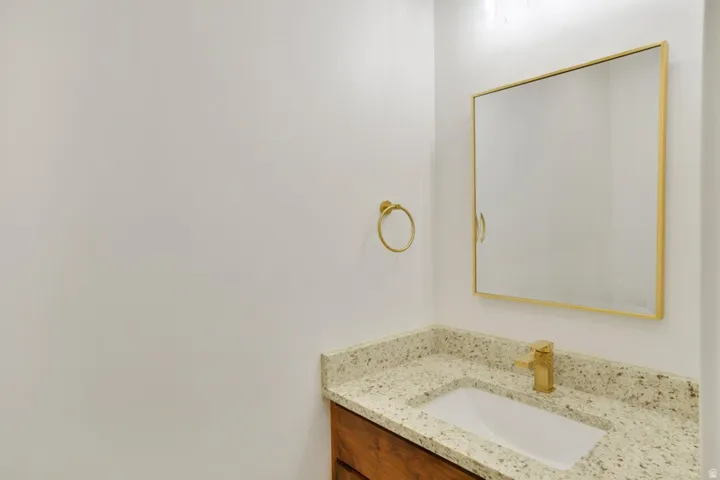 Vanity with a granite-style countertop, undermount sink, and gold-tone faucet