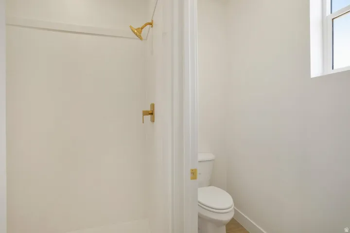 Shower stall with gold-finish fixtures and a window for natural light
