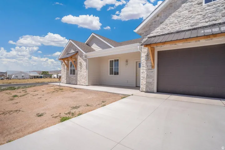 Exterior featuring light-colored stone and horizontal siding, a dark garage door, and a concrete driveway