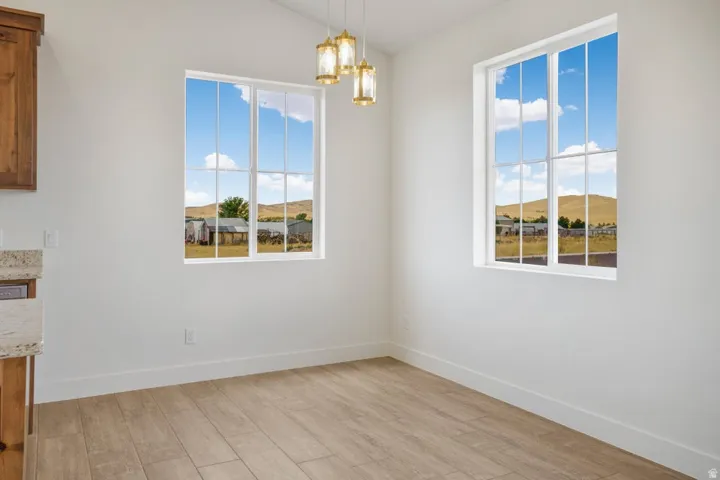 Bright interior space featuring two multi-pane windows, wood-finish flooring, white walls, and a multi-bulb ceiling fixture