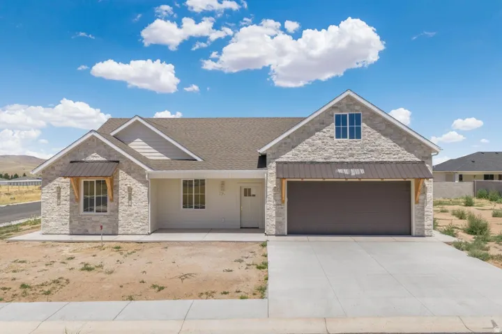 Modern ranch-style home featuring a stone facade, a two-car garage, and a covered entryway