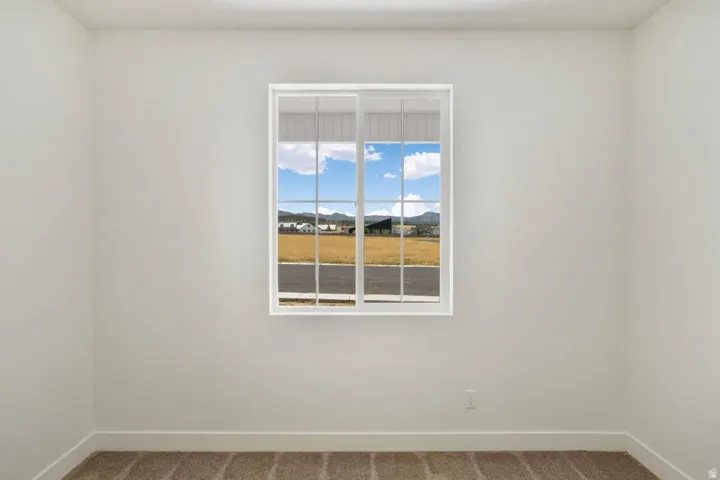 Bright interior space featuring a window with white framing, neutral wall tones, and brown carpeting