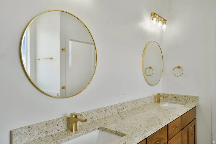 Double vanity featuring light-colored speckled countertops, undermount sinks, and gold-finish faucets