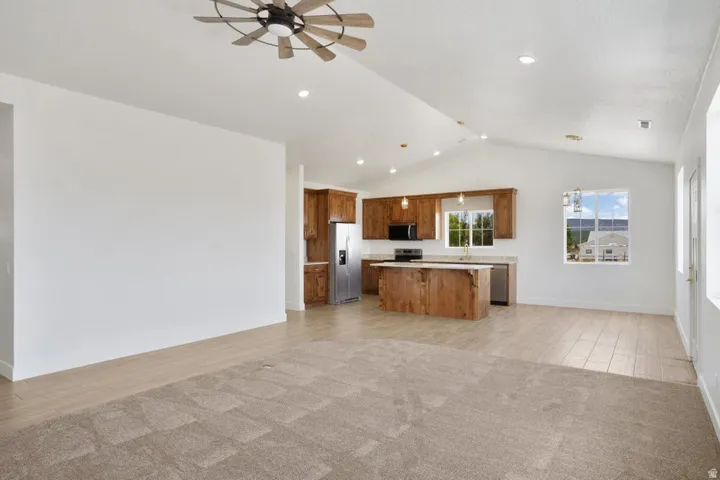 Open-concept living space featuring vaulted ceilings, recessed lighting, and a contemporary ceiling fan