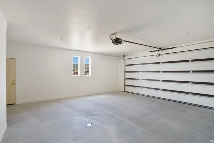 Expansive garage featuring a concrete floor, a sectional overhead door with an automatic opener, and two upper windows