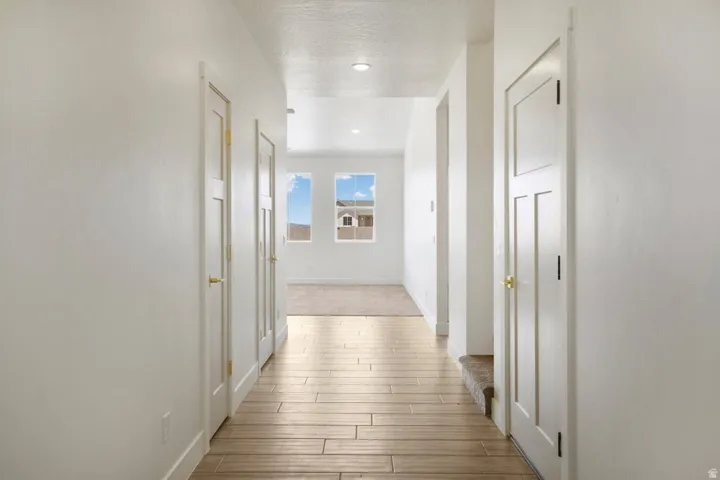 Hallway with wood-finish flooring and bright white walls