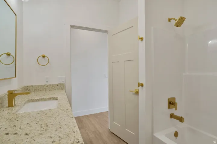 Bathroom featuring a light speckled countertop vanity with an undermount sink and gold-tone faucet
