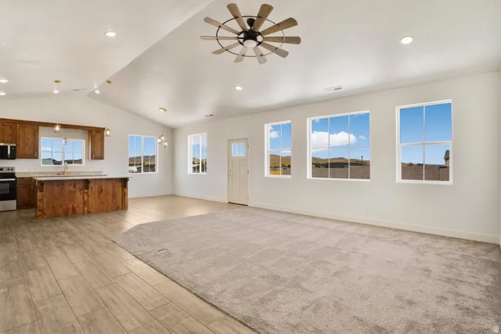 Open-concept living space featuring vaulted ceilings, a contemporary ceiling fan, and recessed lighting