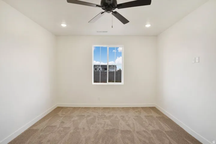 Neutral-toned room featuring a central window, recessed lighting, a ceiling fan, and light-colored carpeting