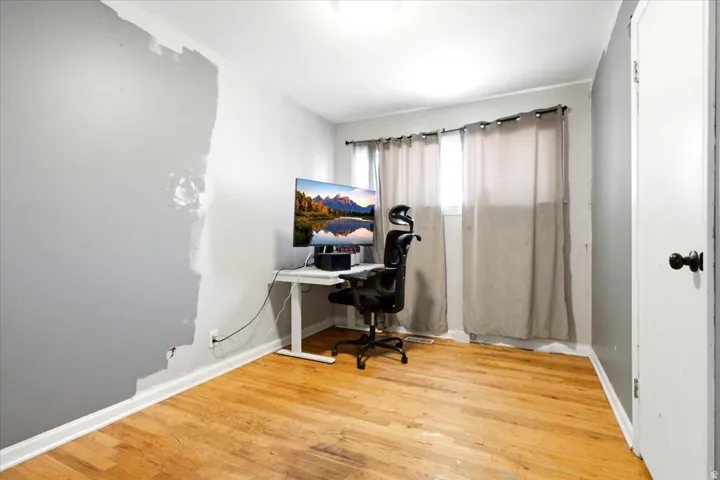 Room featuring wood-finish flooring, white baseboards, and a window with curtain rod