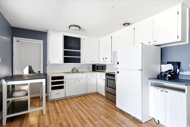 Kitchen space featuring wood-finish flooring and white cabinetry
