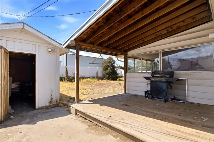 Wood deck patio with a slatted wood ceiling, accompanied by an adjacent shed
