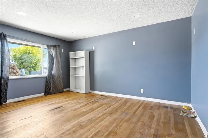 Room featuring wood-finish flooring, a large window, blue painted walls, and recessed ceiling lighting