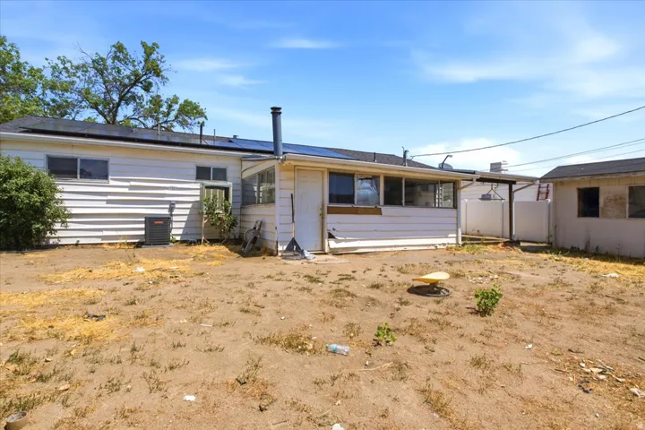 Rear exterior featuring solar panels, white horizontal siding, and multiple windows