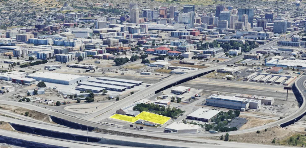 Aerial perspective showcasing a property outlined in yellow, situated near multi-lane roadways and commercial structures