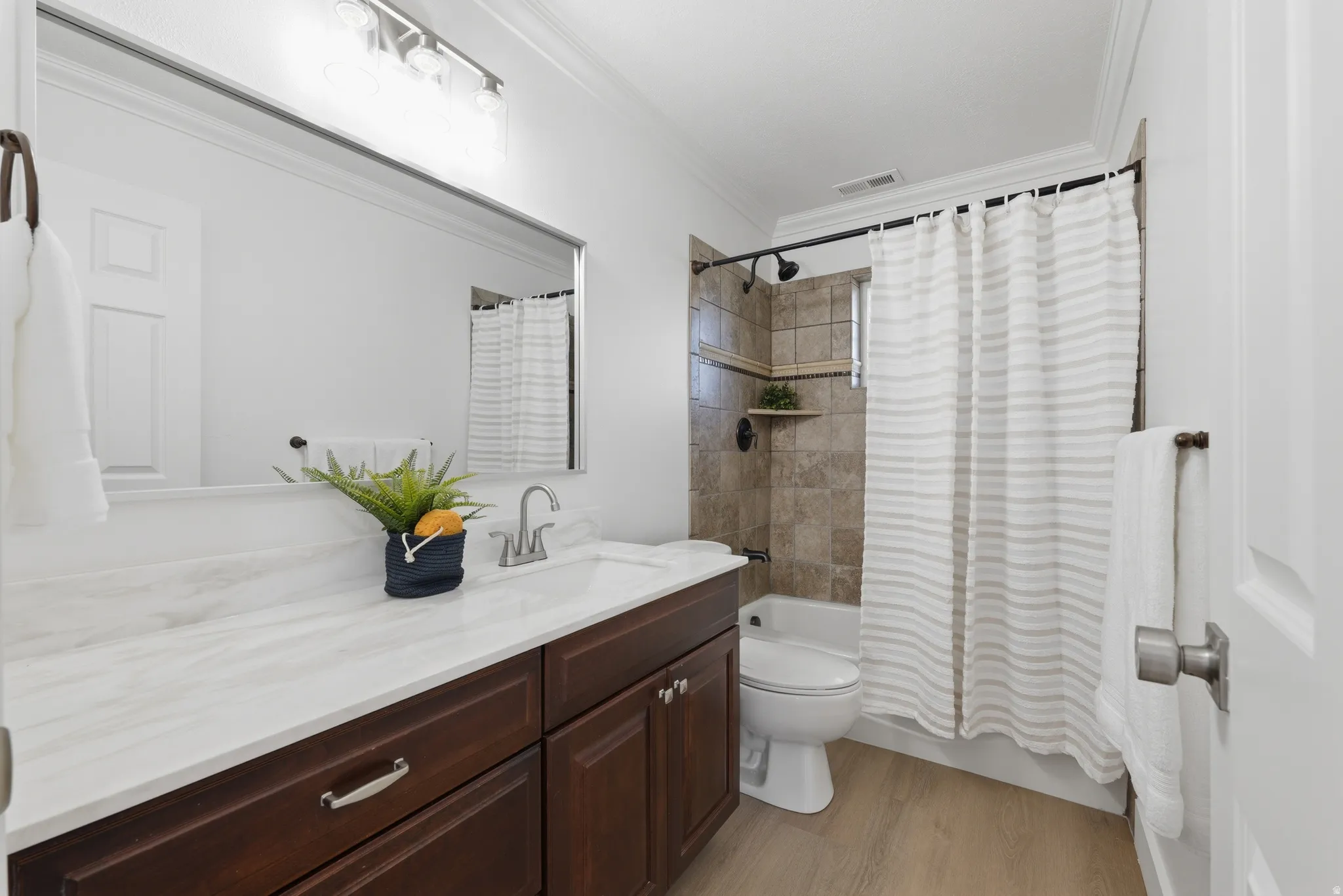 Bathroom featuring a white quartzite countertop, LVP flooring and tub/shower combo.