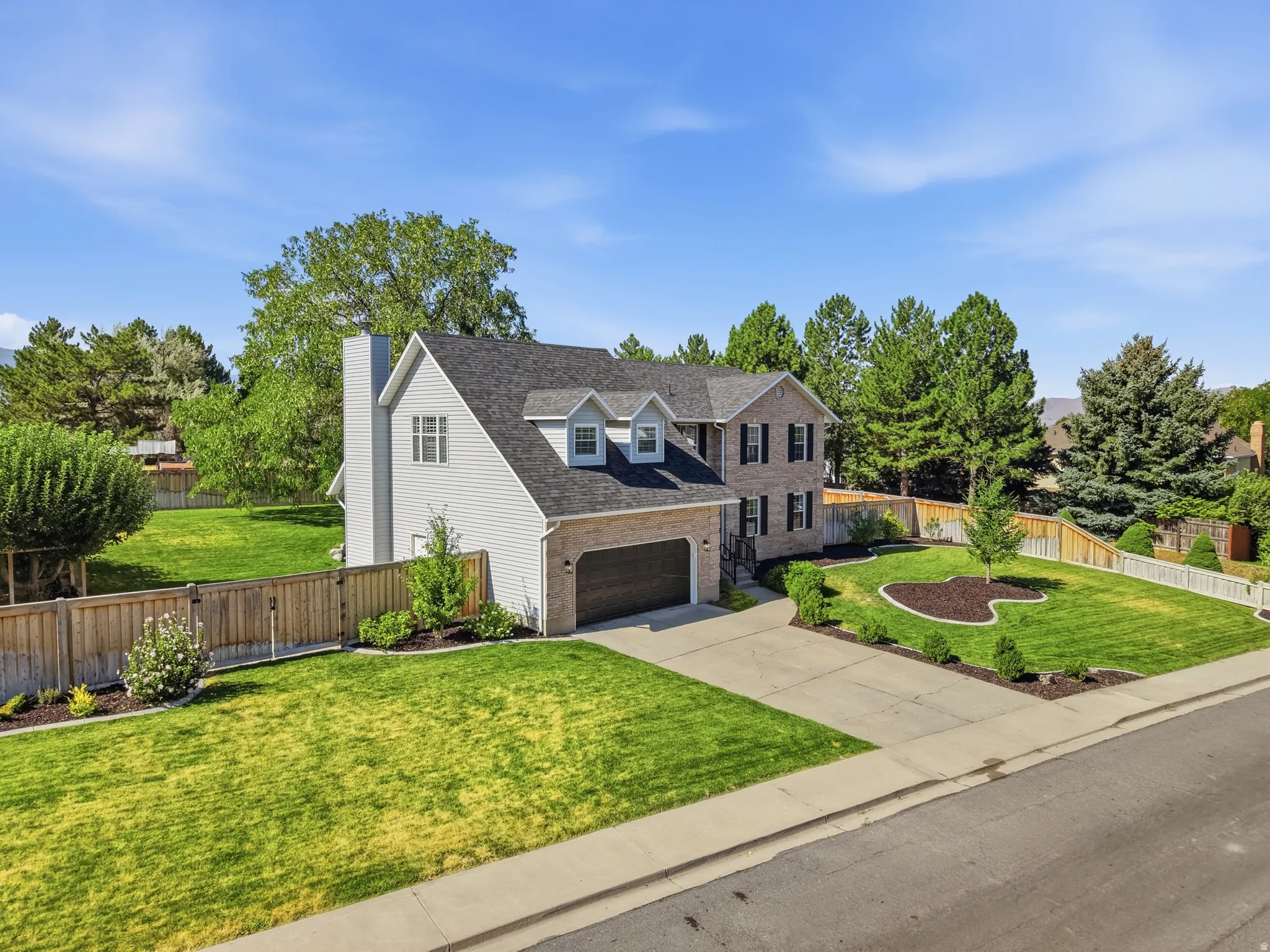 Two-story residence featuring a brick and siding exterior, a two-car garage, and two front dormer windows