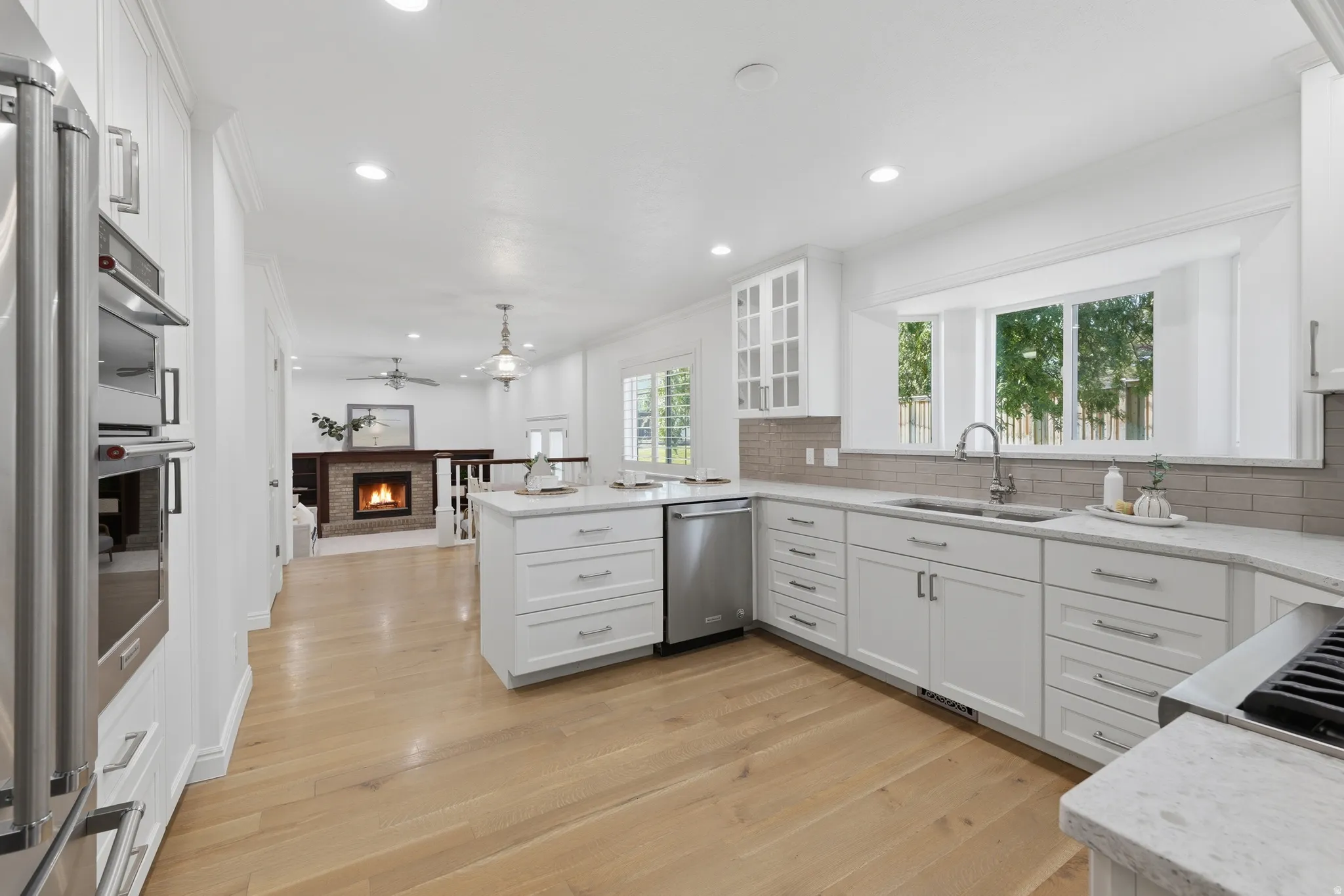 Open-concept kitchen with light hardwood flooring, white cabinetry, and integrated stainless steel appliances.