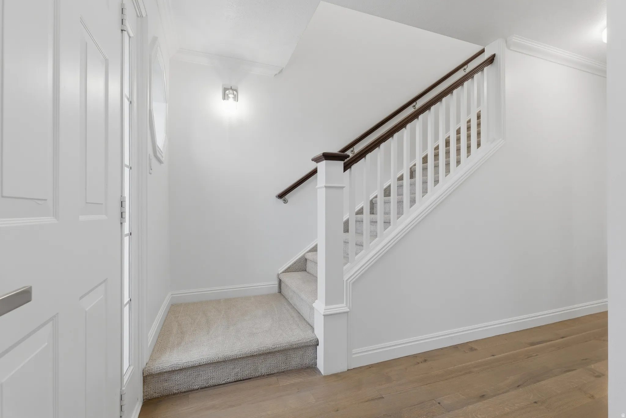 Staircase featuring wood-finish handrails, white balusters, and carpeted treads