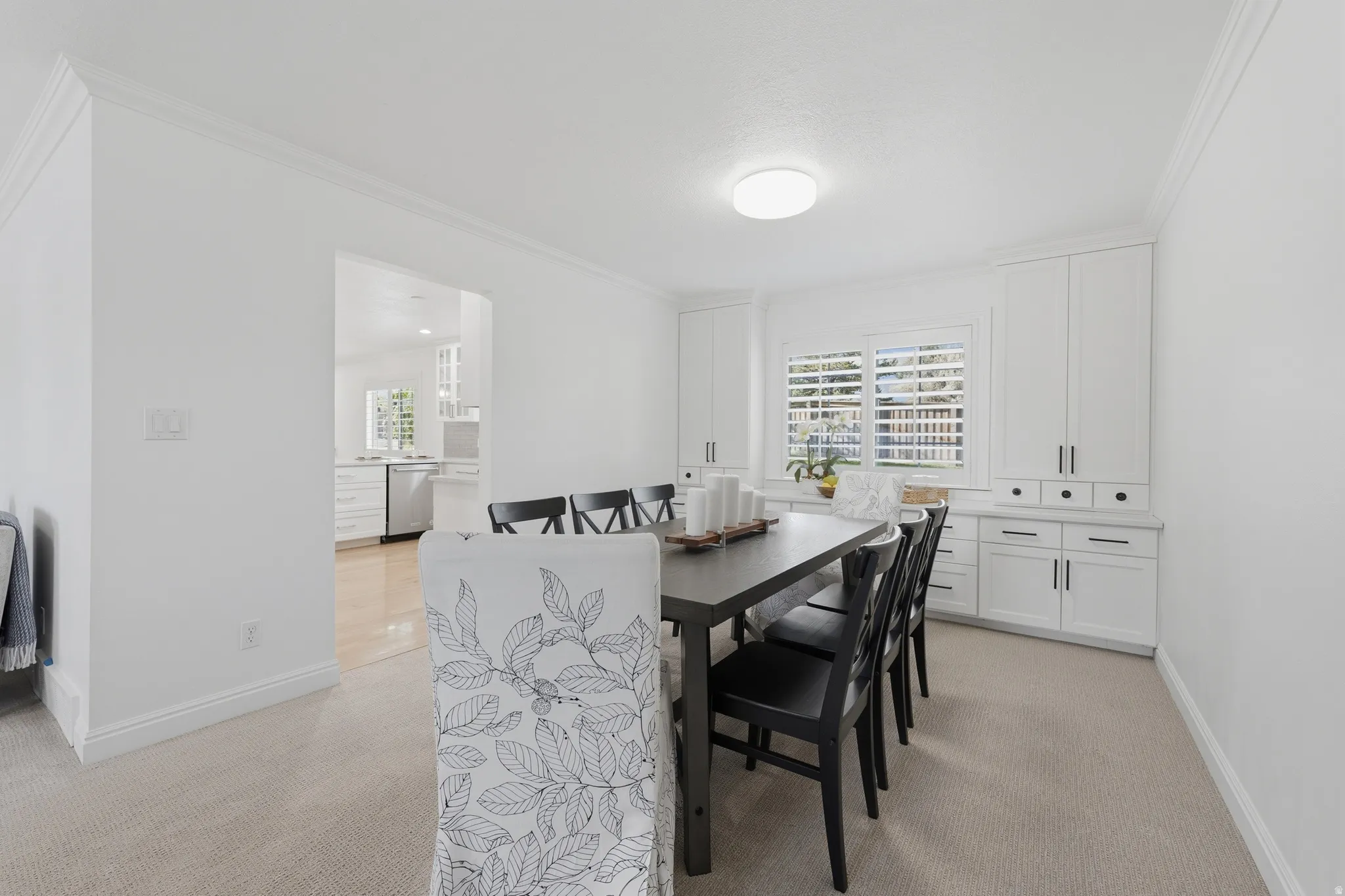 Dining or office area featuring built-in white cabinetry, crown molding, and a carpeted floor