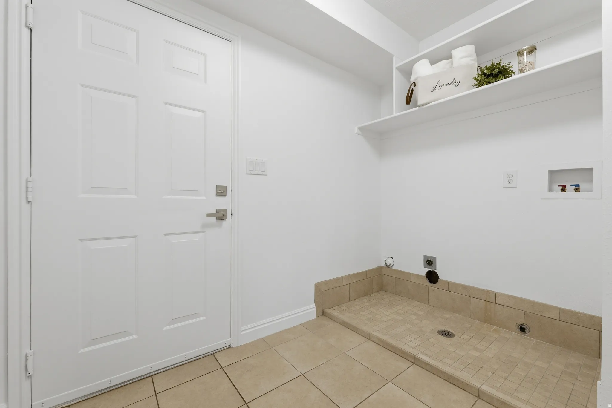 Laundry area with door leading to garage. Includes shelves and storage closet.