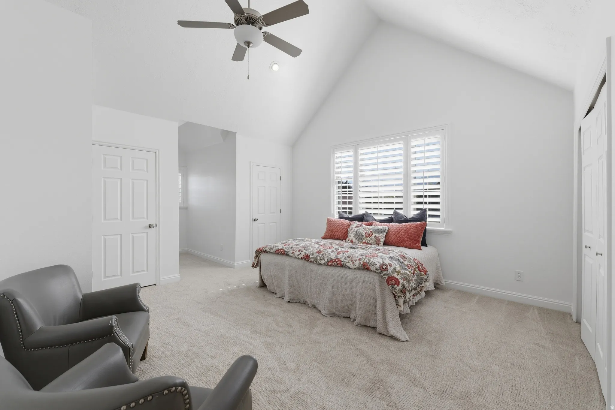 Primary suite featuring a vaulted ceiling with a ceiling fan, light-toned carpeting, and plenty of storage space