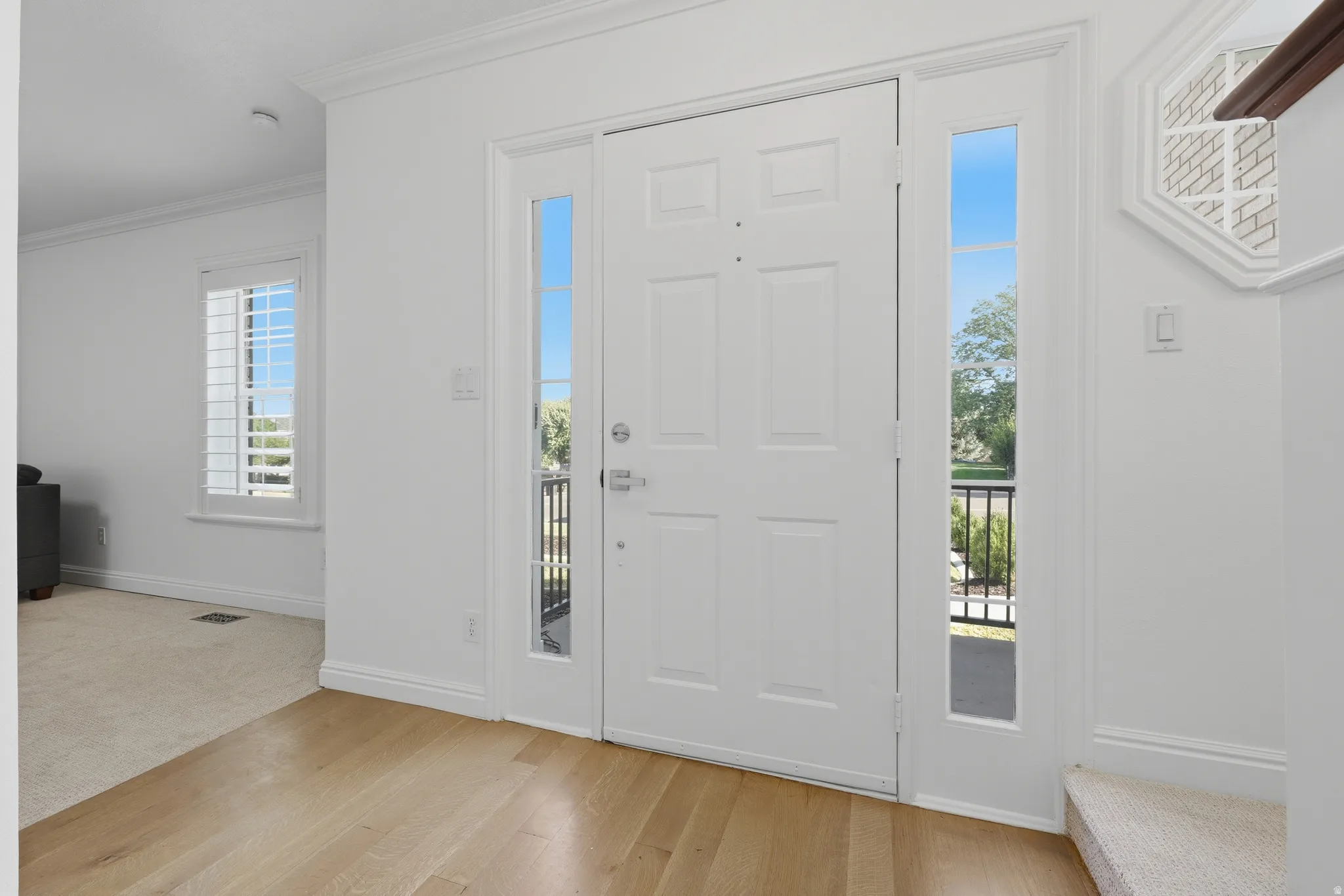Entrance with a paneled door, sidelights, and light hardwood flooring