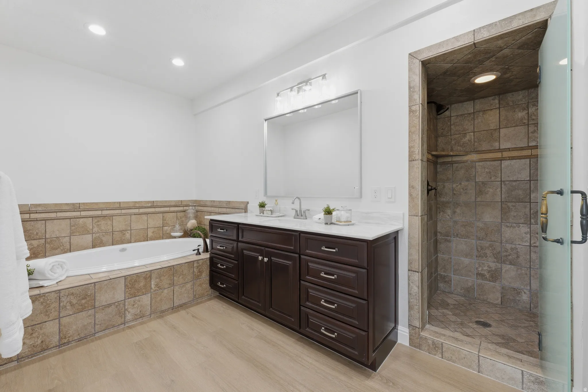 Dual-sink vanity with a white quartzite countertop, LVP floors and walk-in shower