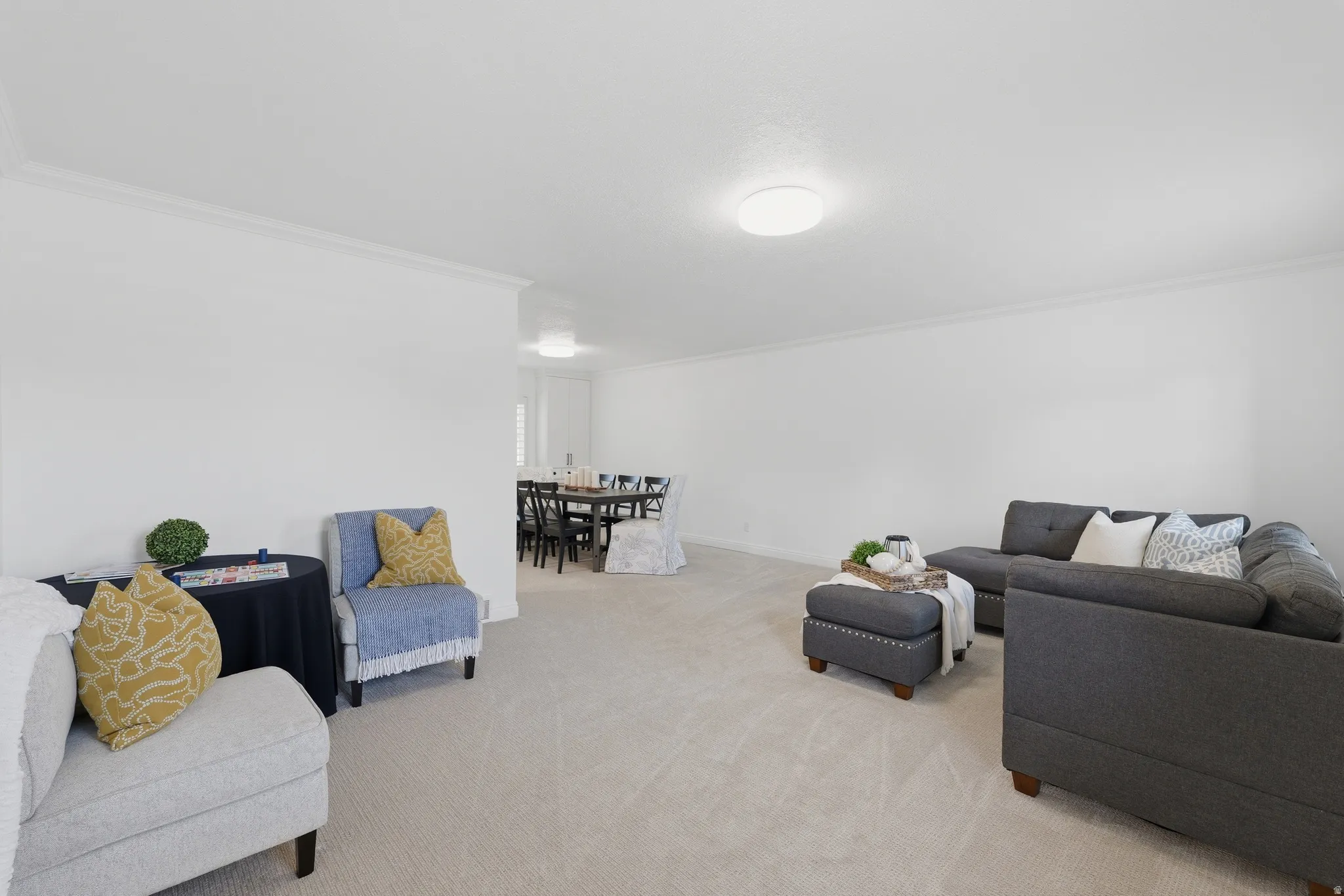 Spacious living area featuring light-toned carpeting and crown molding