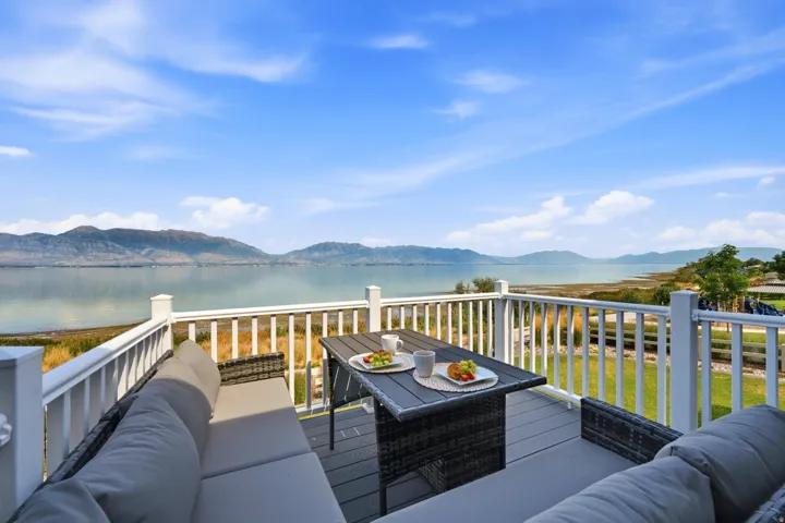Expansive deck featuring white railings, composite decking, and a water backdrop with distant mountains