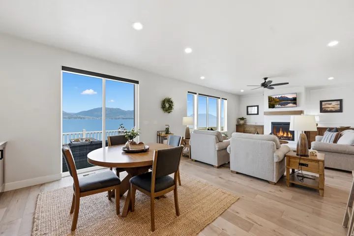 Spacious open-concept living area featuring wood-finish flooring, recessed lighting, and a modern fireplace with a mantel