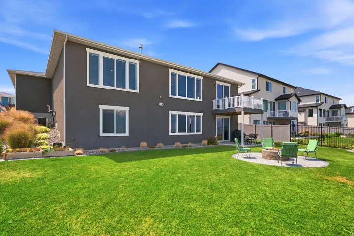 Expansive green lawn with a circular paver patio featuring a built-in fire pit