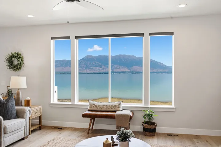Expansive windows with mountain and water backdrop, recessed lighting, ceiling fan, and wood-finish flooring