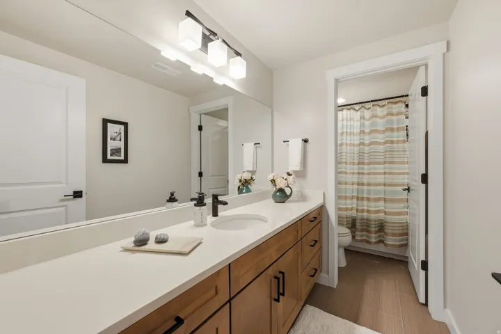 Extended vanity with an integrated sink, broad wall mirror, and modern three-light fixture