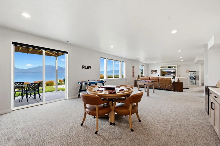 Spacious lower-level area with recessed lighting, large glass sliding door, and multiple windows offering water and mountain scenery