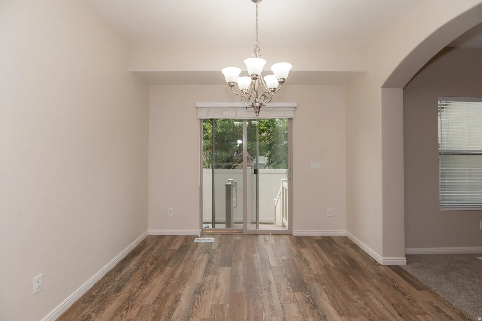 Spacious dining area featuring wood-finish flooring and a contemporary chandelier