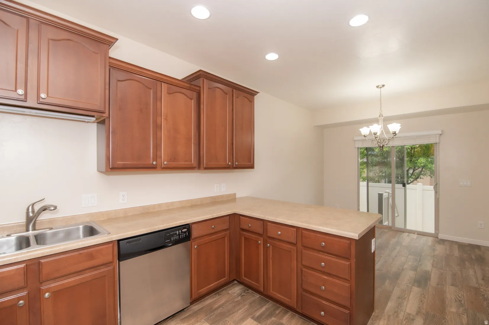 Kitchen featuring wood-finish cabinetry, stainless steel double basin sink, and integrated dishwasher