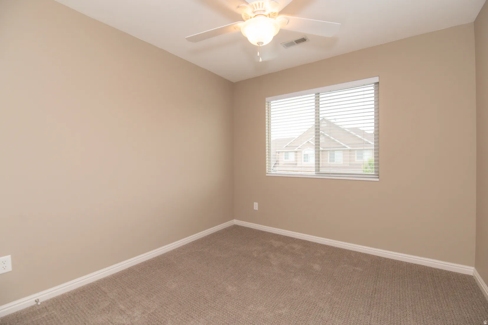 Spacious room featuring neutral carpeting, light beige wall paint, and white baseboards