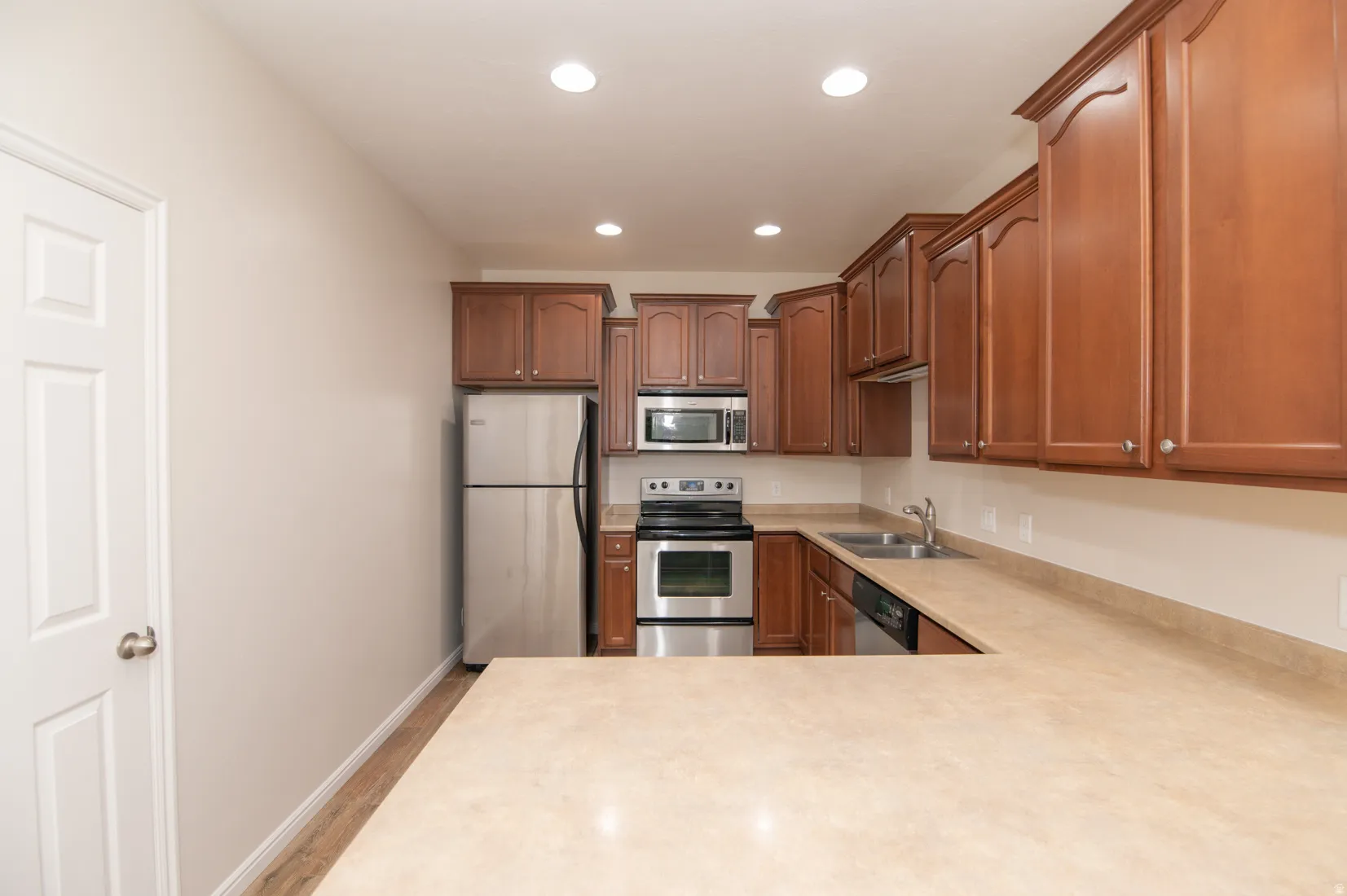 Kitchen featuring wood-finish cabinetry, stainless steel appliances, a double basin sink, and ample countertop space